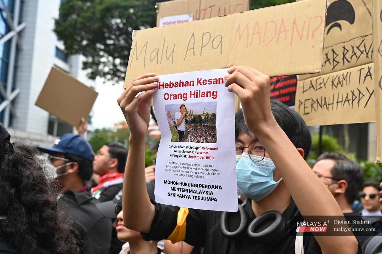 A youth mocks Anwar Ibrahim as a missing person during a protest against the government's failure to fight corruption.