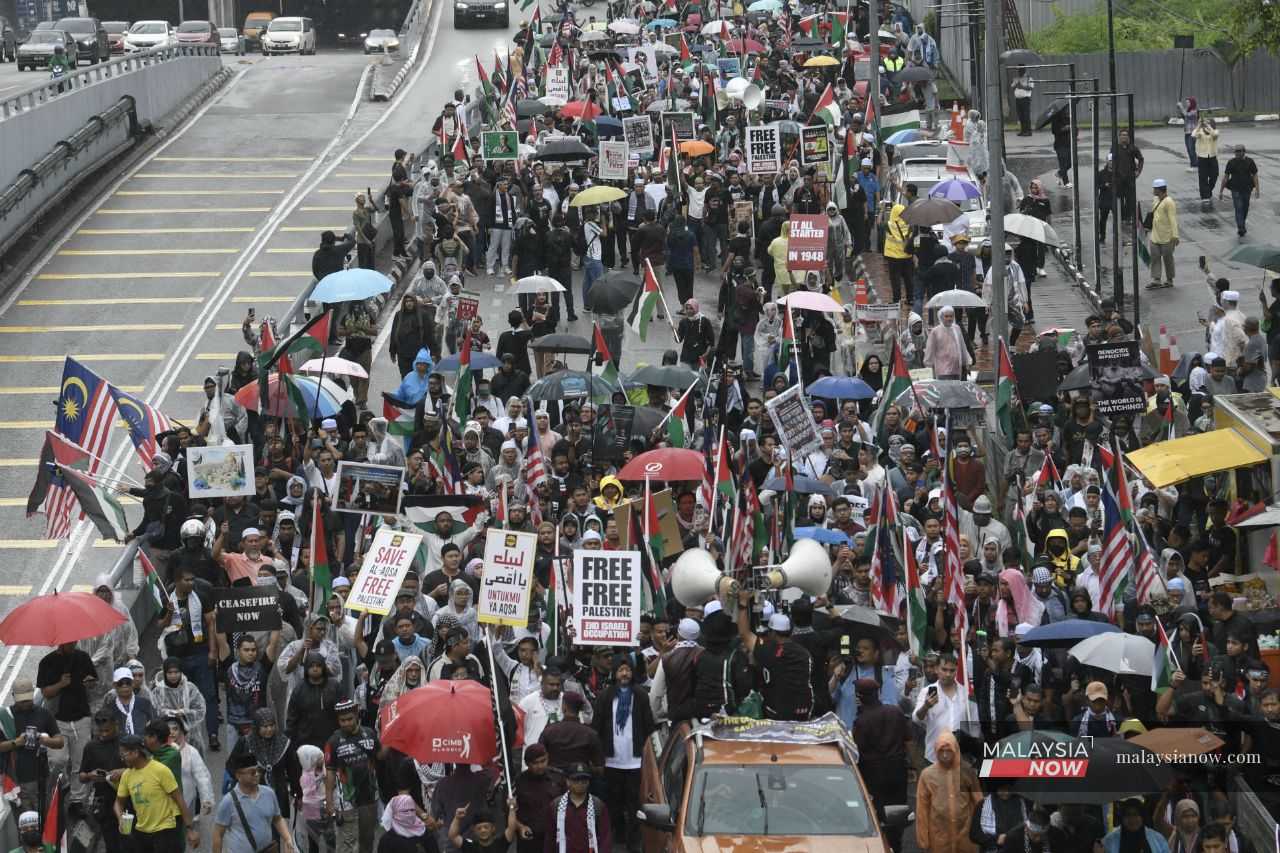 People march in front of the US embassy in Kuala Lumpur to protest President Donald Trump's planned visit later this month.