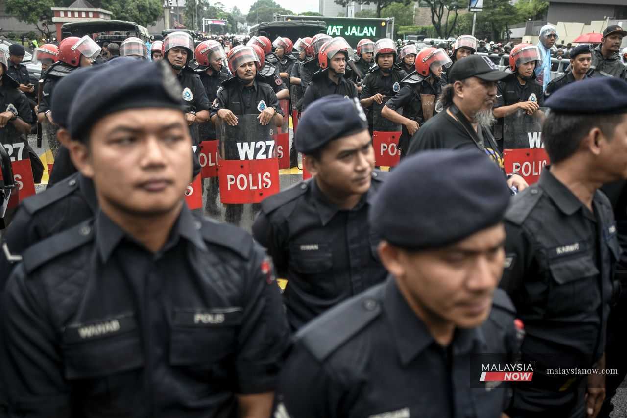 Police officers and anti-riot personnel stand for hours watching the protests unfold outside the US embassy.