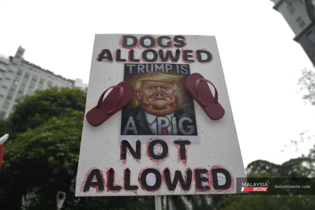 A protester displays a placard mocking Donald Trump during a rally in Kuala Lumpur to protest the US leader's visit to Malaysia this month.